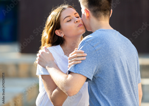 Foto Young man and girl are hugging and kissing each other in cheek