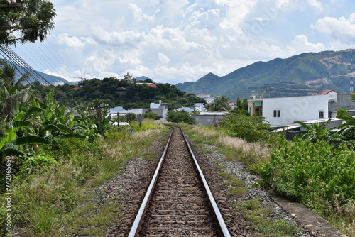 Rails on the railway leading to the city against the backdrop of mountains and blue sky.