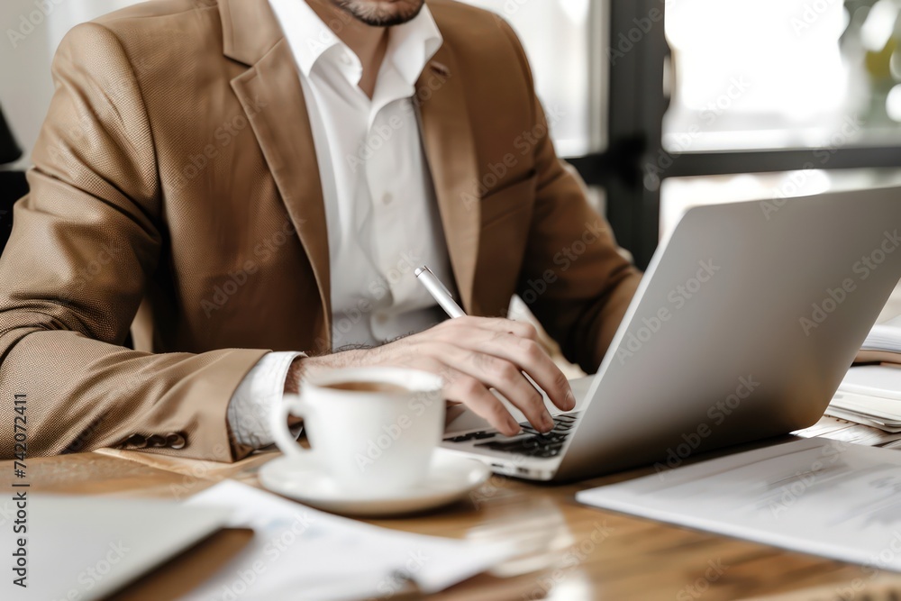 man in suit sitting on laptop at office working on documents, light white and brown man in suit sitting on laptop at office working on documents, light white and brown