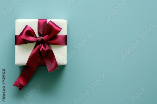 a gift box with a red ribbon and bow on a light blue background