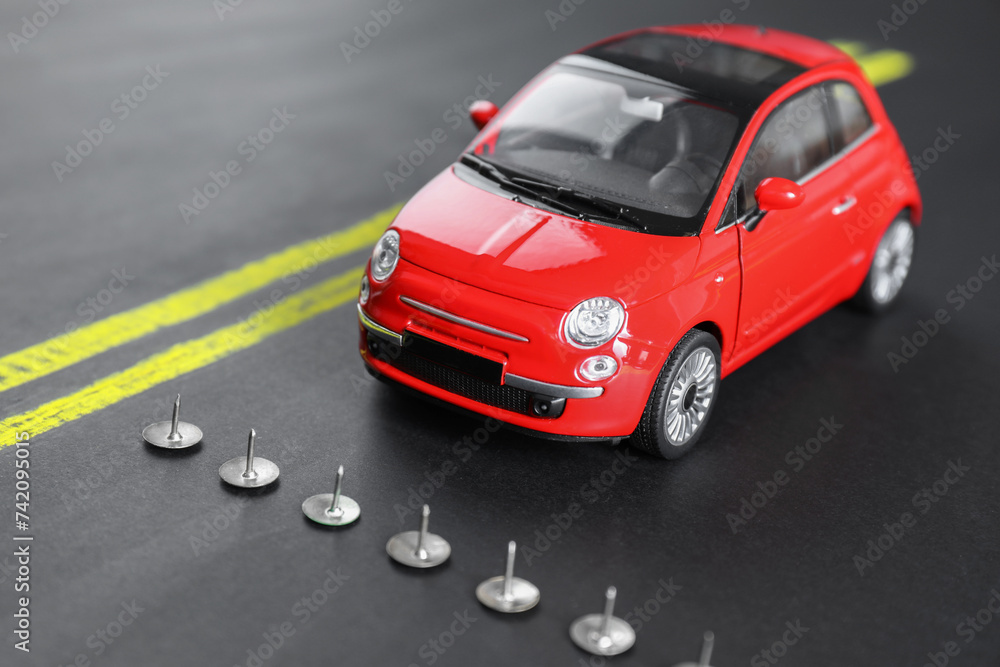 Pins as barrier blocking way for red toy car. Development through obstacles overcoming