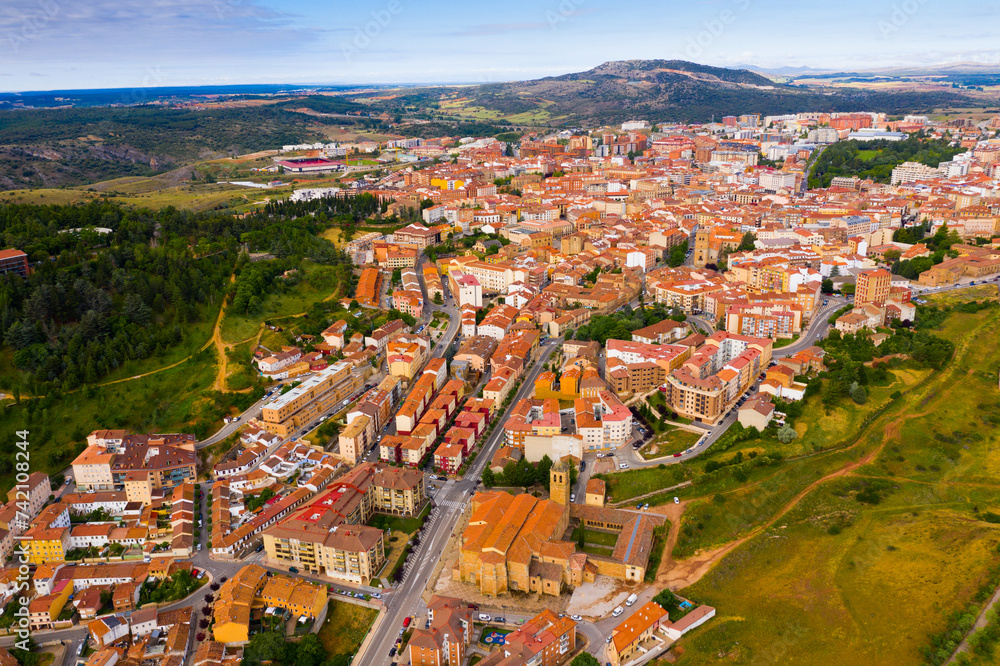 Aerial view of small Spanish city of Soria on background of picturesque landscape with river and green hills ..