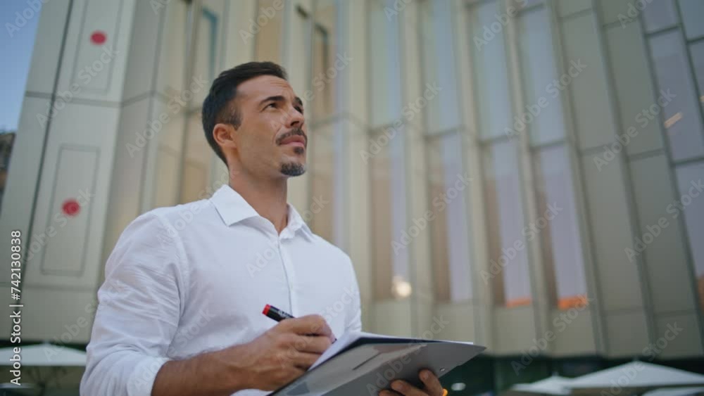 Confident man studying documents at street on go closeup. Businessman crossing Confident man studying documents at street on go closeup. Businessman crossing