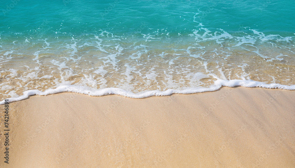 Soft wave of the turquoise sea on the sandy beach. Natural summer background with copy space