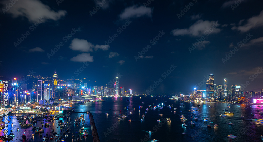 Night view of a city skyline and crowded harbor with bright lights reflecting on water