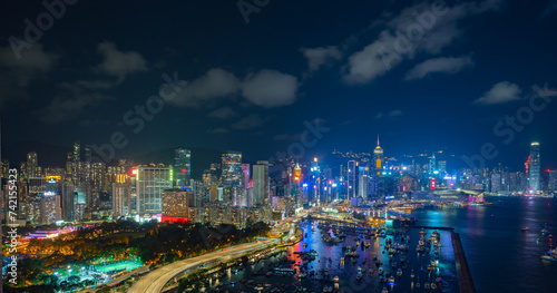 Night view of a city skyline and crowded harbor with bright lights reflecting on water