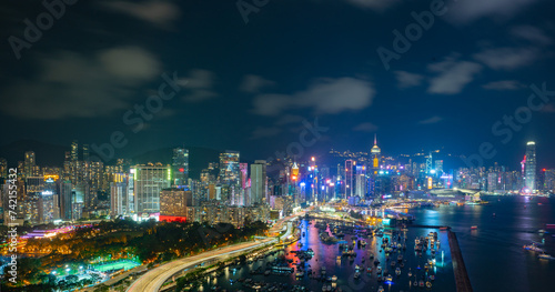 Night view of a city skyline and crowded harbor with bright lights reflecting on water