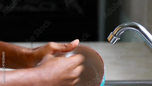 Male hands washing and rinsing bowl with soapy sponge and water in kitchen photo