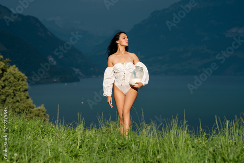Woman milky body. Sexy woman with milk in Alps. Young woman in lingerie hold milk outdoor on farm. Alpine country girl. Sensual woman with milk near Swiss Alps. Girl hold bottle of fresh milk in the