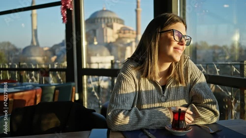 Happy woman enjoying tea with hagia sophia view in istanbul. photo