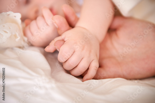 Bed, holding hands and parent with infant, care and support with maternity, health and wellness at home. Fingers, family and love with a healthy baby, protection and child development with bonding