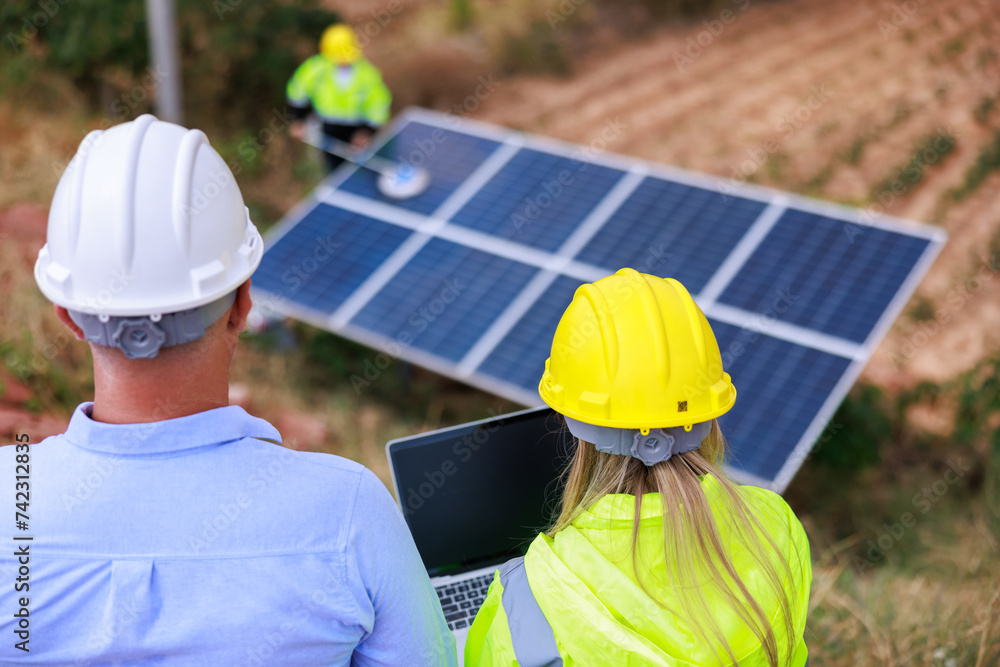 technician specialist and engineers examining solar panel using digital laptop computer in solar farm. solar panel cleaning officer background.. technician specialist and engineers examining solar panel using digital laptop computer in solar farm. solar panel cleaning officer background..