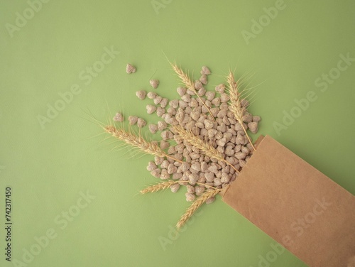 Extruded bran in the shape of a heart is poured out of the package onto a green background. Spikelets of wheat. The layout for the label. A place for the text