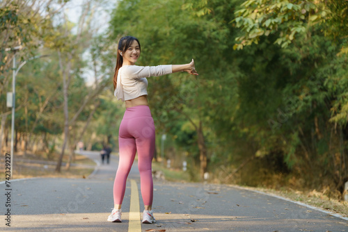 Young female runner stretching arms before running in the morning. Women stretch to warm up before running or working out. Fitness and healthy lifestyle concept.