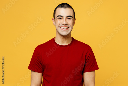 Young smiling happy cheerful fun cool satisfied middle eastern man he wearing red t-shirt casual clothes looking camera isolated on plain yellow orange background studio portrait. Lifestyle concept. © ViDi Studio