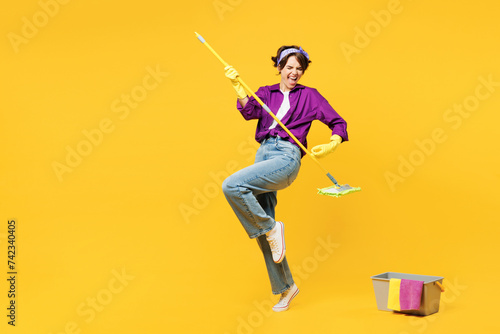 Full body young woman wear purple shirt casual clothes do housework tidy up pov play guitar hold mop bucket water wash floor isolated on plain yellow background studio portrait. Housekeeping concept. photo