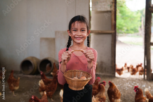 A 8 years old elementary girl is happy smiling in chicken farm. Concept of farm school, montessori, self learning in edcuation system, sustainability, healthy lifestyle and activity for kid learning. photo