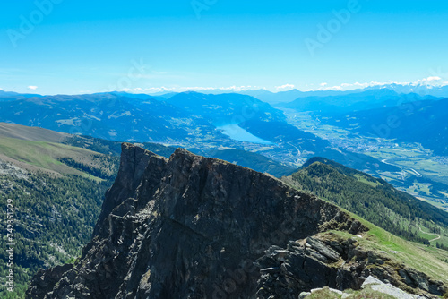 Idyllic hiking trail on alpine meadow with scenic view of lake Millstatt seen from mountain peak Boese Nase in Ankogel Group, Carinthia, Austria. Remote landscape in majestic Austrian Alps in summer