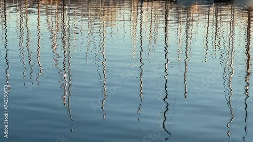 Reflection of yachts and sailboats on sea surface at marina photo