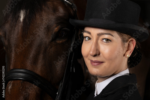 Dressage rider head portraits, with top hat next to her horse. photo