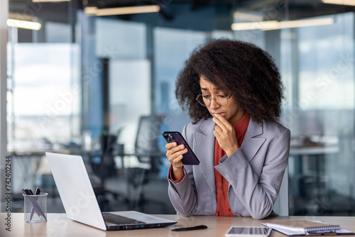 Photography Sad woman with bushy hairstyle touching mouth with fingers with pitiful expression while using mobile telephone