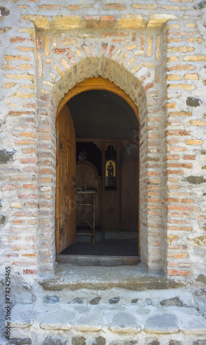 Portal to the church. Entrance arch made of bricks  stone steps  visible icon in the interior.
