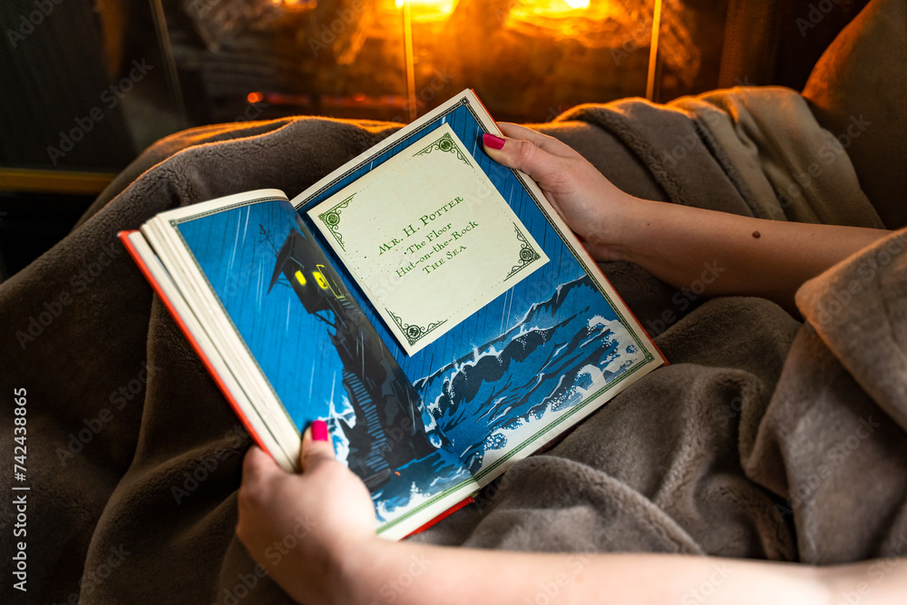 Fototapeta premium Teenage girl reading the first book about Harry Potter near the fireplace.