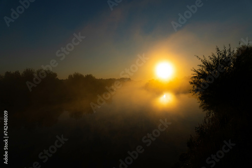 Panorama of beautiful misty lake coast at sunrise moment.