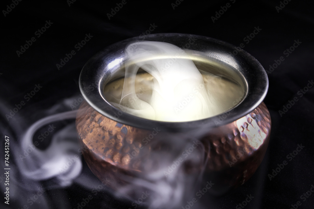 Brass copper metal style pot cauldron smoke vape fog lit inside rising flowing moving rotate on black background Brass copper metal style pot cauldron smoke vape fog lit inside rising flowing moving rotate on black background