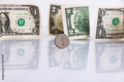 UAE currency dirham coin, on the background of paper American dollars. Copy space.