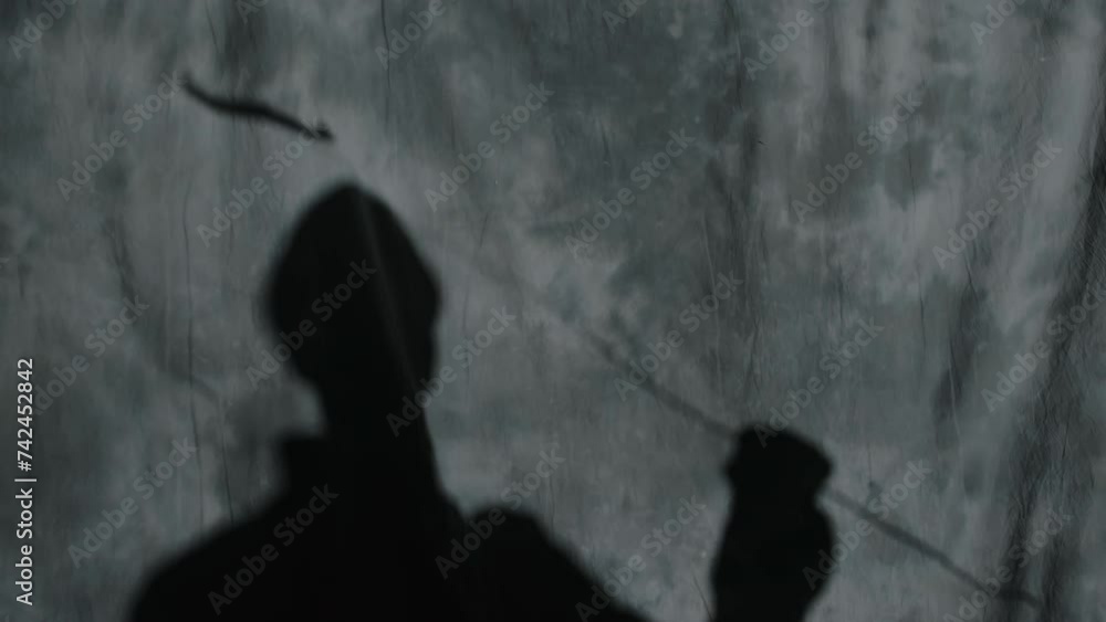 Unrecognizable mime theatre artist playing game of shadows on dark stage in spotlight, operating handmade butterfly on stick and imitating fly Unrecognizable mime theatre artist playing game of shadows on dark stage in spotlight, operating handmade butterfly on stick and imitating fly