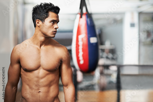 Boxing, training and man in gym for exercise, practice and fitness for health. Personal trainer, serious expression and thinking with confidence for workout, planning and vision with shirtless body