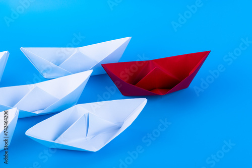 Fototapeta Naklejka Na Ścianę i Meble -  Red, white paper ship on a blue background. Leader concept. Copy space.