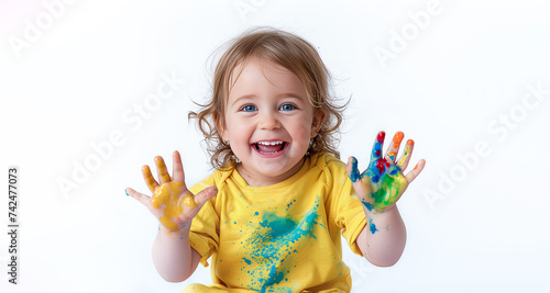 A cheerful little girl in a yellow T-shirt shows her dirty hands. Creativity  play  cheerful little child with paint  banner with space for text on a white background. Happy childhood