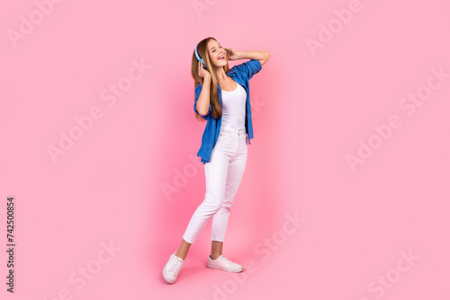 Full length photo of excited cheerful lady dressed blue shirt enjoying songs earphones singing isolated pink color background © deagreez