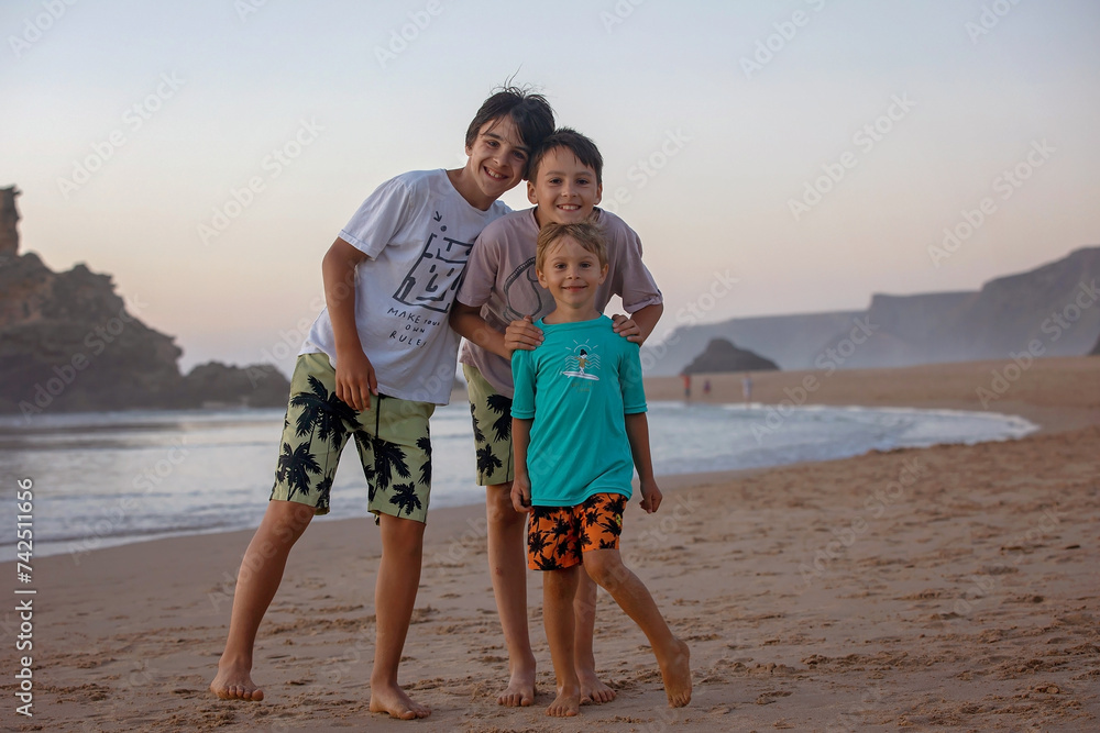 Happy children, boys, playing on the beach on sunset, kid cover in sand, smiling, laughing Happy children, boys, playing on the beach on sunset, kid cover in sand, smiling, laughing