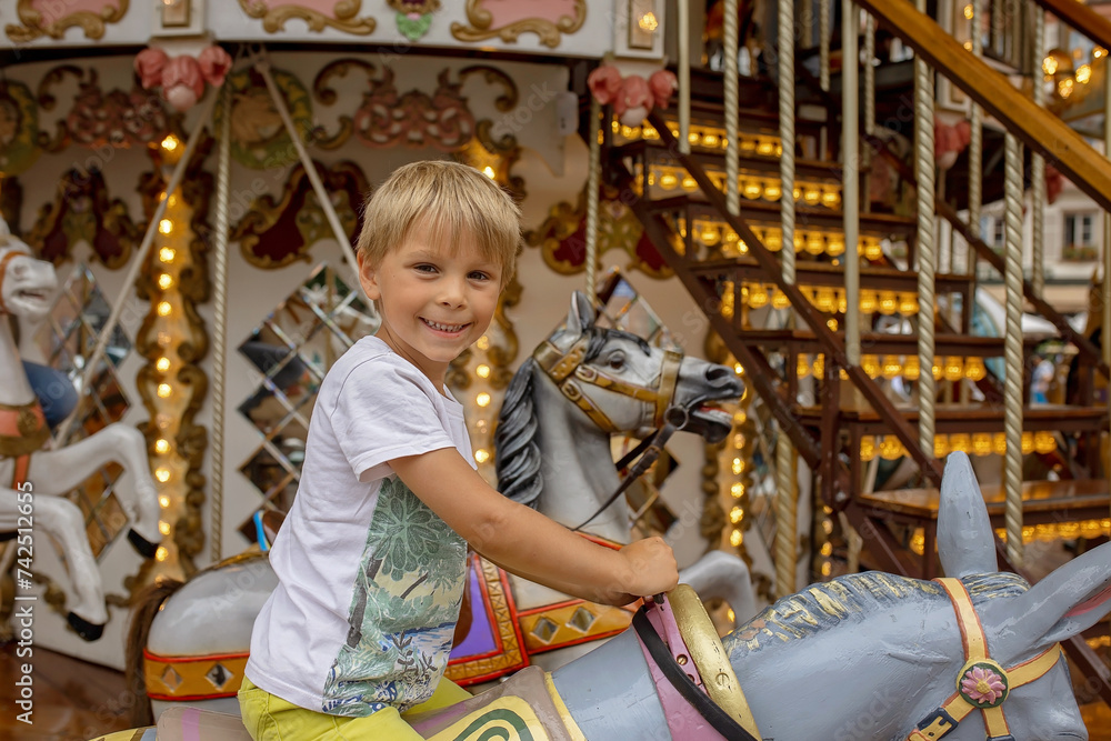 Children, boys, going on Merry Go Round, kids play on carousel in the summer