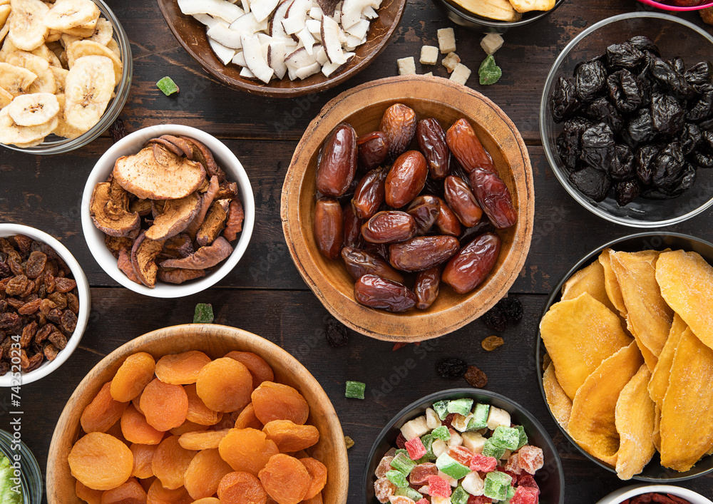 Fototapeta premium Mixed healthy dried sweet berries and fruits snack in various bowl plates on wooden background.Top view.