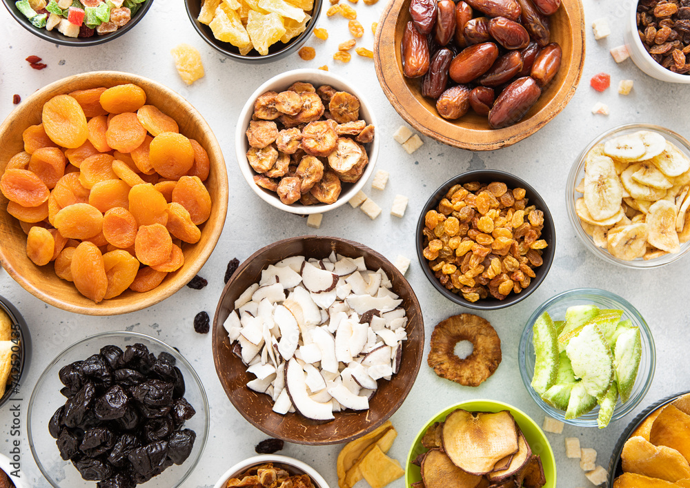 Assorted organic dried sweet fruits and berries in various bowl plates on light kitchen background.Top view. Assorted organic dried sweet fruits and berries in various bowl plates on light kitchen background.Top view.