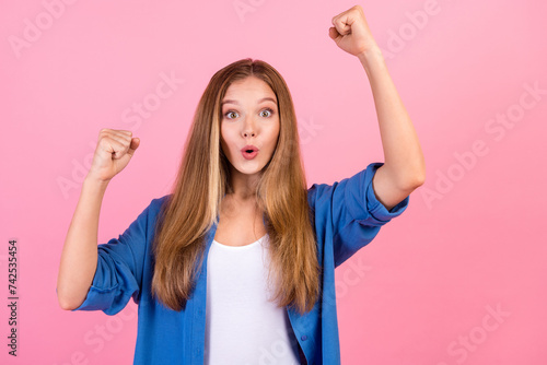Photo of good mood lucky lady dressed blue shirt yelling yeah rising fists empty space isolated pink color background