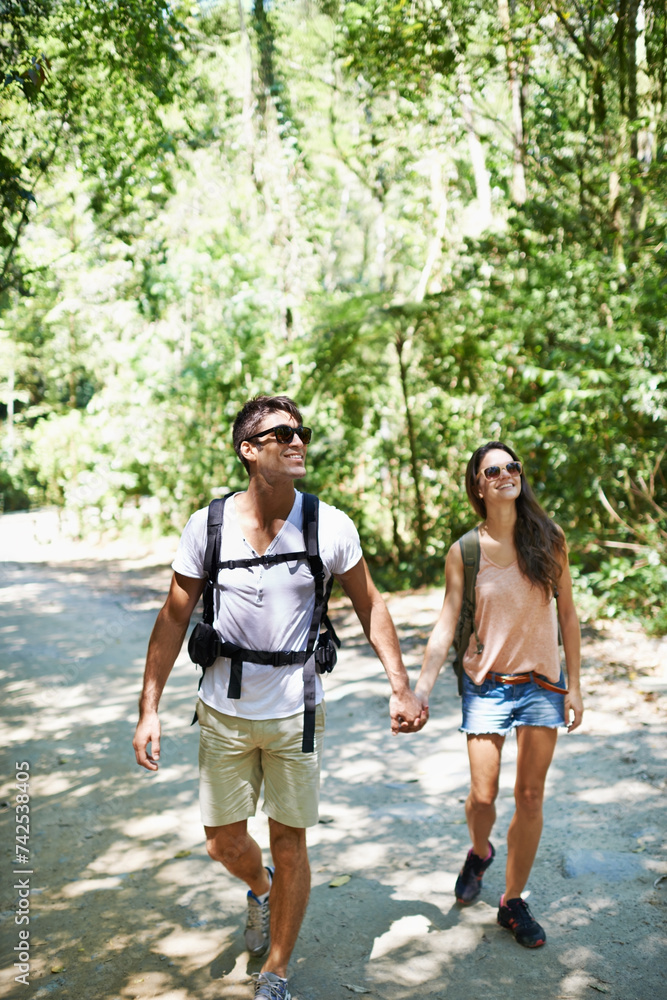 Fototapeta premium Walking, hiking and couple holding hands in nature for adventure, freedom and backpacking outdoors. Travel, bonding and man and woman on trail for holiday, vacation or trekking for wellness in forest