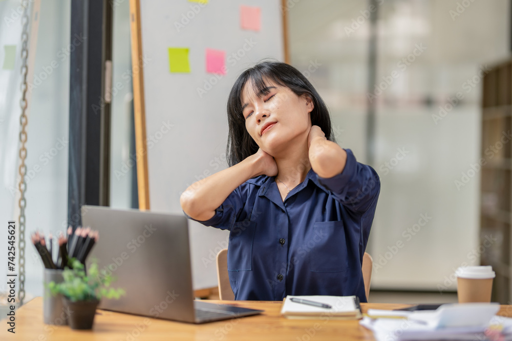 A female employee stretching lazy at the desk to relax while working in the office. Feeling stressed and achy from work. A female employee stretching lazy at the desk to relax while working in the office. Feeling stressed and achy from work.