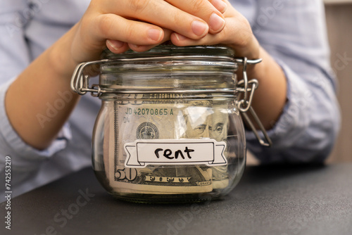 Obraz na plátně Female hands holding Glass jar full of American currency dollars cash banknote with text RENT