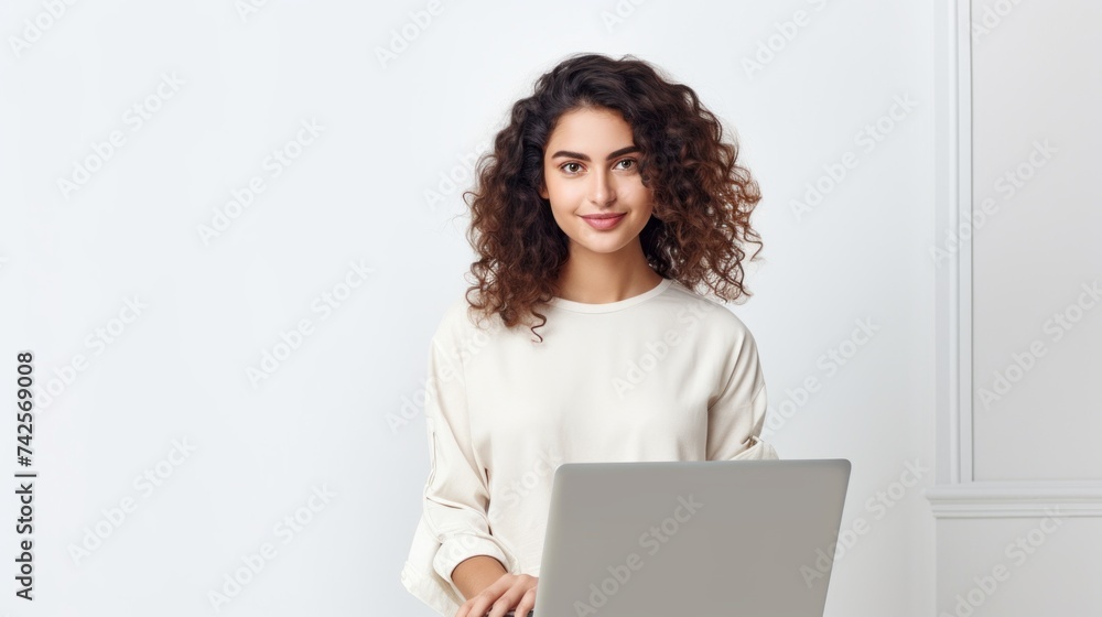 A smiling young woman, creative graphic designer, freelancer, retoucher wearing casual clothes, holding a laptop and looking at the camera on a white background with copy space. A smiling young woman, creative graphic designer, freelancer, retoucher wearing casual clothes, holding a laptop and looking at the camera on a white background with copy space.