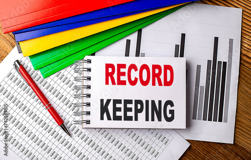 RECORD KEEPING text on notebook with pen, folder on a chart background