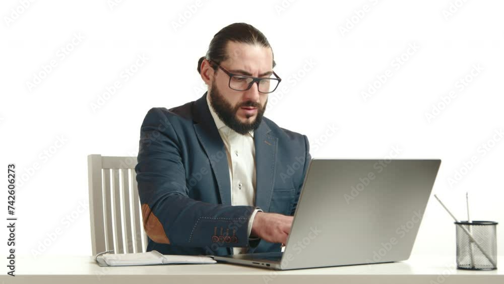 Focused businessman in a suit jotting down notes in a notebook beside a laptop on a white desk, symbolizing organized work habits. Ideal for business planning and productivity topics. Camera 8K RAW. Focused businessman in a suit jotting down notes in a notebook beside a laptop on a white desk, symbolizing organized work habits. Ideal for business planning and productivity topics. Camera 8K RAW.