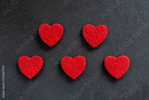 Red fabric hearts on the black stone background.