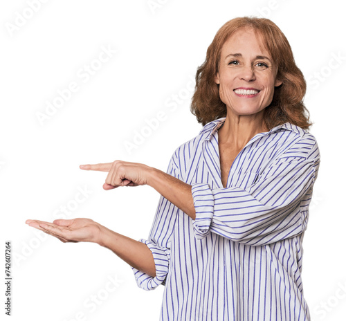 Redhead mid-aged Caucasian woman in studio excited holding a copy space on palm.