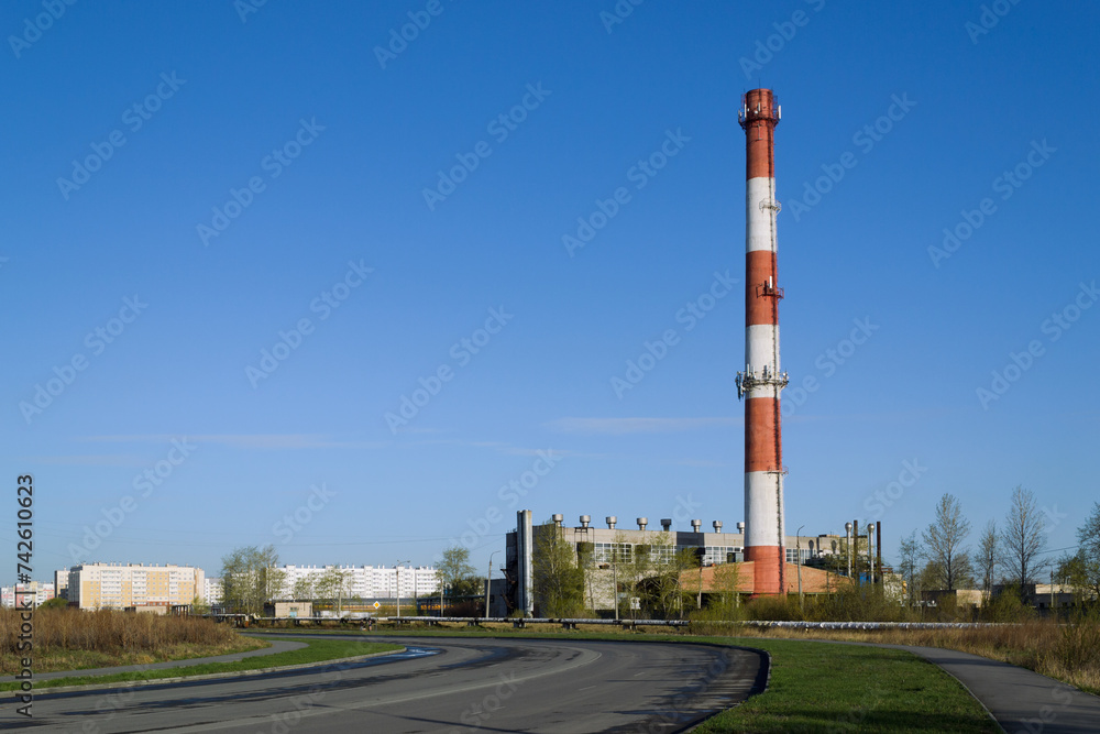 The tall red and white chimney of the boiler house against the blue sky