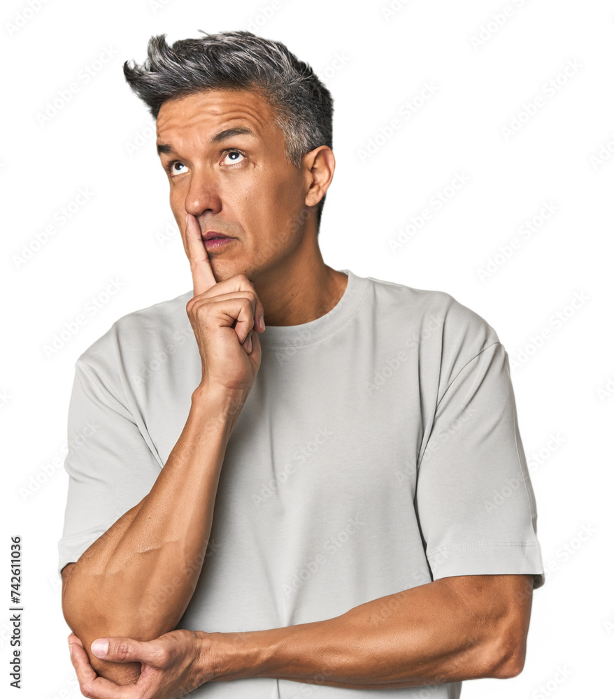 Middle-aged Latino man looking sideways with doubtful and skeptical expression. Middle-aged Latino man looking sideways with doubtful and skeptical expression.
